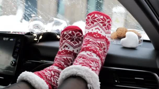 車のダッシュボードの冬時間に赤いニットの靴下でリズミカルに女性の足を移動します 明けましておめでとうございます — ストック動画