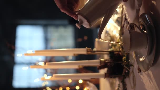 急須からお茶を注ぐ女性 クリスマステーブルのセッティング 熱いお茶を注ぐのクローズアップビューでは 蒸気カップから出てくる クリスマス 垂直ビデオ — ストック動画