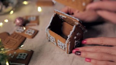 Kadın ve çocuk elleri Noel için zencefilli kurabiye evi yaptı. Noel süslemeleri, kış aile aktiviteleri