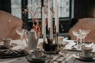 Noel sofrası, fincanlar, çaydanlık, mumlar, beyaz masa örtüsüne servis edilen bardaklar. Sıcak bir Noel yemeği, akşam yemeği ve çay saatine hazırlanıyorum..
