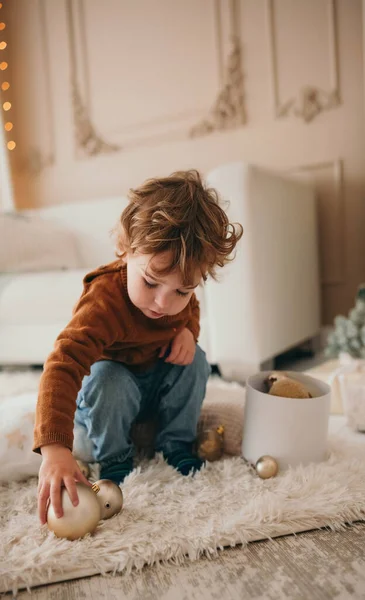 可爱的卷曲头发蹒跚学步的男孩玩圣诞球 舒适的圣诞之家 — 图库照片