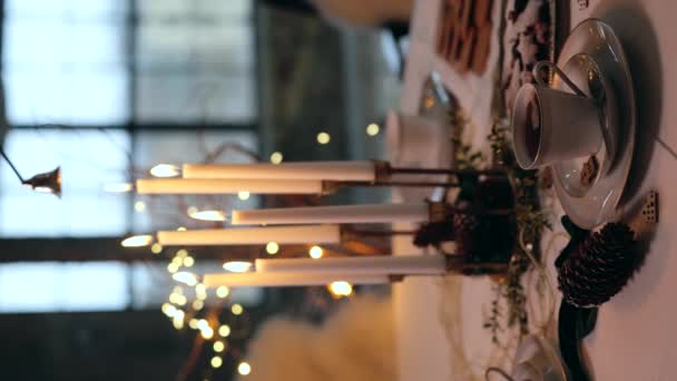女性の手はキャンドルスナッファーで燃えるろうそくを消滅させます グラスキャンドル 紅茶用カップ 自然植物の枝のクローズアップビュー クリスマス 垂直ビデオ — ストック動画