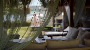 Beautiful view on empty sofa and waving in the wind curtains in a summer cafe in the outdoors. Summer vacations.