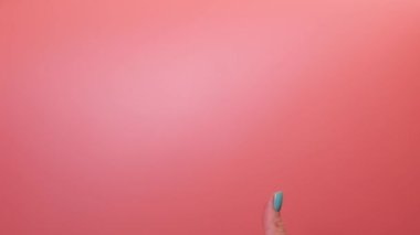 Woman hand on pink background gesturing with thumb up YES. Hand communication