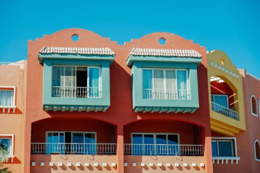 Colourful red house with blue balcony against blue sky in sunny day