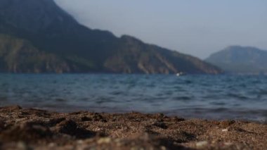 Akdeniz ve dağ manzaralı karanlık kumlu sahilde alçak görüş açısı. Seyahat yeri, tatil konsepti. Türkiye, Adrasan