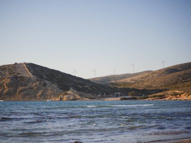 Günbatımında okyanus kıyılarında rüzgar türbini jeneratörleri. Yunanistan 'ın Rodos kentinde alternatif yenilenebilir enerji üretimi