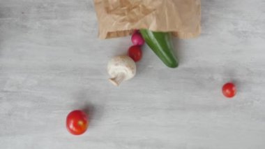 High angle top closeup view fruits and vegetables fall out small paper bag. Healthy food home eco delivery concept