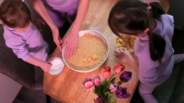 キッチンで一緒にパン屋を準備している幸せな家族 母親と2人の子供の娘がアップルパイを調理する 自家製の食べ物や小さなヘルパー 生地の調製 — ストック動画