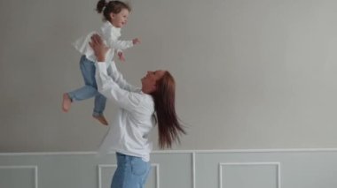 Küçük kızıyla oynayan mutlu genç anne onu kaldırıyor. Anne ve kızı birlikte eğleniyorlar.