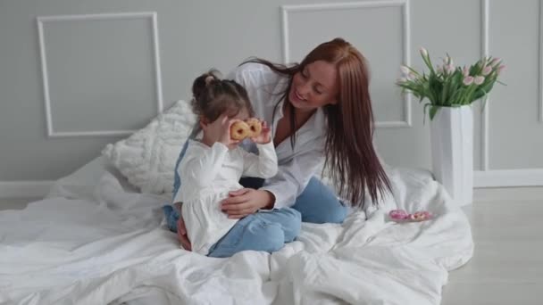 Szczęśliwa Młoda Mama Bawiąca Się Swoją Córeczką Trzymającą Słodkie Pączki — Wideo stockowe