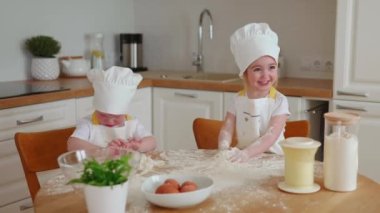 Aşçı şapkalı ve önlüklü sevimli reklamcı kız mutfakta unla oynuyor. Çocuklar hamur hazırlıyor, mutfakta un uçuruyor. Yavaş çekim
