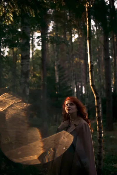 秋の森の夕日の時間にベージュのコートで美しい夢のような赤い髪の女性 顔に日没の光 懐中電灯からのバックライト レンズフレア効果 — ストック写真