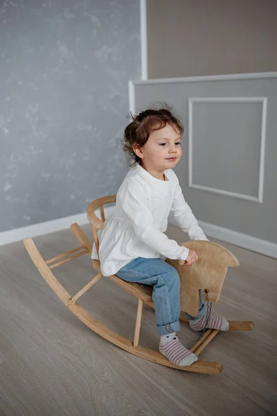Nettes Emotionales Zweieinhalbjähriges Mädchen Das Drinnen Auf Einem Holzpferd Schwingt — Stockfoto