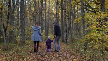 Mutlu bir aile. Anne, baba ve iki yaşındaki kızları sonbahar yapraklarını toplayarak ormanda yürüyorlar. Aile hafta sonu yürüyüşü