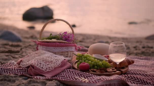 美しい夏のピクニックは 白ワイン クロワッサン クッキー 新鮮な果物とビーチで日没で1人のために提供しました — ストック動画