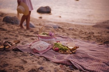 Güzel yaz pikniği plajda beyaz şarap, kruvasan, kurabiye ve taze meyvelerle servis edilir. Arka planda kadın bacakları