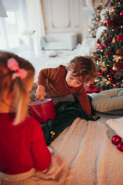 Küçük çocuklar Noel süslemeli yatak odasında yatakta oynuyorlar.