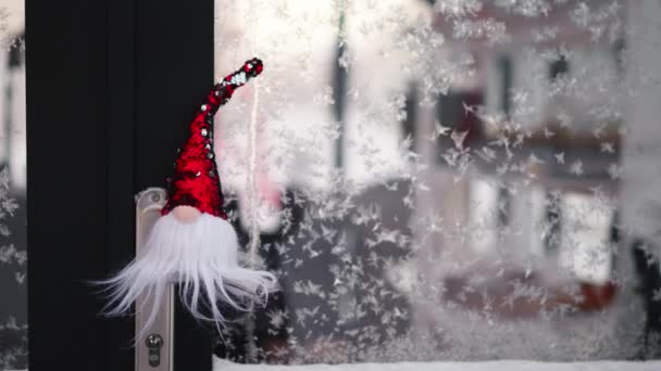 Malý Vánoční Skřítek Červeným Kloboukem Venku Zamrzlém Okně Sněžný Sváteční — Stock video