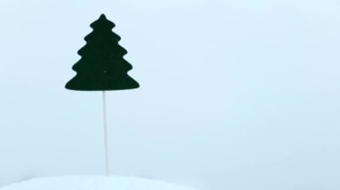  Mini süslenmemiş yapay Noel ağacı kara saplanmış. Kar yağıyor. Noel tatili kavramı