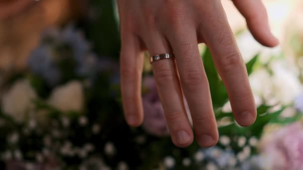 Close Van Bruiloft Paar Handen Dragen Gouden Ringen Bloemen Achtergrond — Stockvideo