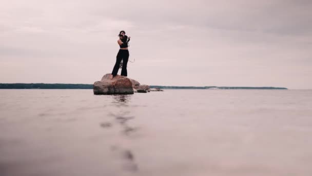 穿着黑色衣服的当代舞蹈家在海中的岩石上跳舞 时尚舞蹈表演 现代舞蹈表达 — 图库视频影像