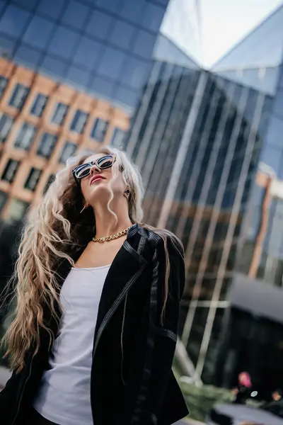 Siyah Ceketli Uzun Sarı Saçlı Şehirde Poz Veren Güneş Gözlüklü Stok Fotoğraf