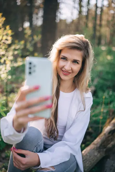 Sarışın Uzun Saçlı Gülümseyen Genç Bir Kadın Ormanda Cep Telefonu Telifsiz Stok Fotoğraflar