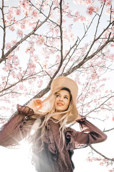 若いセンセーショナルかわいいブロンドの女性の肖像画 花開く桜の木に立って 美しい太陽の光線 ロイヤリティフリーのストック画像