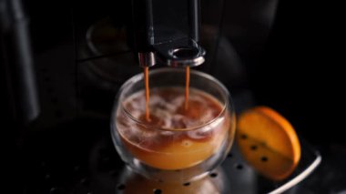 Makineden portakal suyu ve çift katlı duvar bardağına kahve dökülüyor. Evde ya da barda portakal suyu ile espresso yapmak.. 