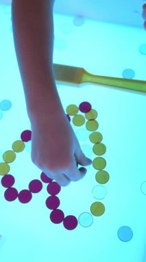 Duyusal kutuda oynayan çocuğun yakın görüntüsü Metal Rimmed Chips 'i kalp şeklinde yapar