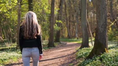 Bahar ormanlarında yürüyen genç bir kadının portresi etrafında dönüyor. Doğanın tadını çıkarıyorum. Eğlence konsepti