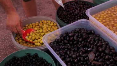 Satıcı yeşil zeytinleri plastik bir torbaya koyar. Antalya Türkiye 'deki doğu sokak pazarında yeşil ve siyah zeytinler.