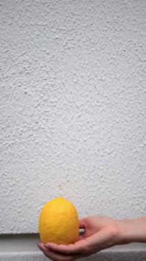 Beyaz duvar arkasına sulu limon atan bir kadın eli..