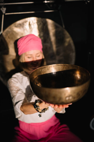 Крупный план женщины, использующей пение чаши в звуковой терапии исцеления в помещении. Избавление от негативной энергии