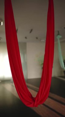 Sinek yogası için kırmızı hamak boş güneşli stüdyoda asılı, yakın çekim. 