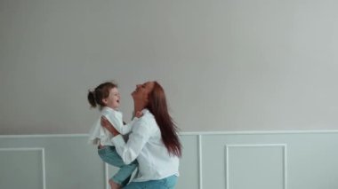 Küçük kızıyla oynayan mutlu genç anne onu kaldırıyor. Anne ve kızı birlikte eğleniyorlar.