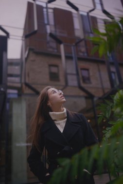 Şehirdeki yemyeşil bitkilerin arasında duran bir insan eşsiz mimari tasarıma hayran..