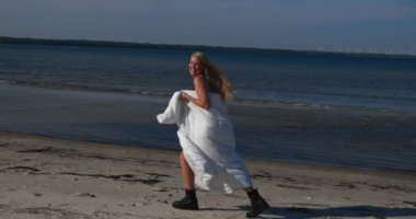 Mutlu kadın kumlu sahilde gezer, havluya sarınır, sakin suların ve günbatımının tadını çıkarır..