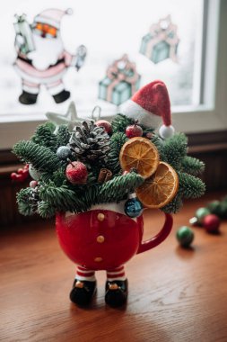 Noel ve yeni yıl çörekleri ve pencerenin yanındaki masada duran bir kasede güzel bir Noel buketi. Noel dekoru. Kış tatili konsepti. 