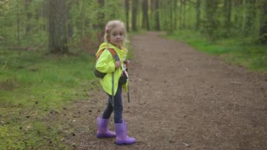 Anaokulundaki mutlu kız, sonbahar ormanı başlarında sırt çantasıyla yürüyor. Çocuklarla açık hava aktiviteleri