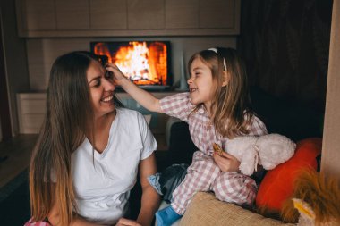 Genç bir kız, sıcak ateşin yanında annesiyle keyifli bir etkileşimi paylaşıyor..