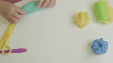 Genç eller canlı plastiği çeşitli araç ve renklerle çevrili yaratıcı tasarımlara dönüştürür..