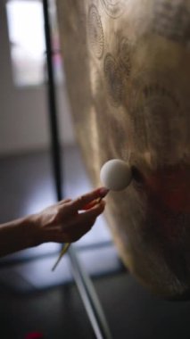 Kadın yoga stüdyosunda küçük yumuşak bir tokmakla gong sesi çıkarıyor. İçeride ses iyileştirme terapisi. 