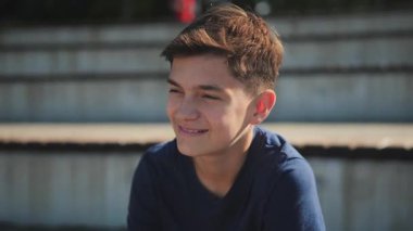 Neşeli bir genç, güneşli bir öğleden sonra parkta doğanın tadını çıkarırken rahatlar ve gülümser..