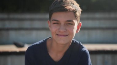 Neşeli bir genç, güneşli bir öğleden sonra parkta doğanın tadını çıkarırken rahatlar ve gülümser..