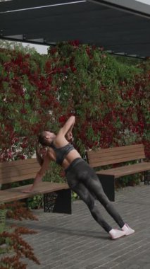 Bir kadın, canlı sonbahar yapraklarıyla çevrili bir parkta esneme hareketleri sergiliyor..