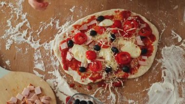Sevimli gülümseyen 3 yaşındaki aşçı şapkalı ve önlüklü kız mutfakta pizza pişiriyor, pizza tabağına malzemeler koyuyor. Çocuk hobileri