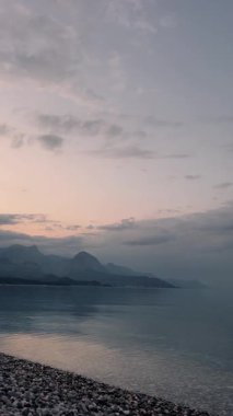 Sakin suların ve etrafındaki dağların altındaki kayaların olduğu berrak kıyı bölgesinin nefes kesici manzarasının tadını çıkarın. Akşam vakti. Kemer, Antalya Türkiye