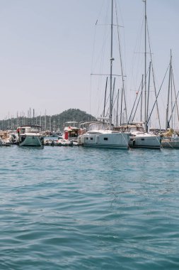 Gocek - Fethiye, Türkiye - 10 Mayıs 2025: Yelkenliler ve yatlar açık mavi bir gökyüzünün altında limana demirlediler.